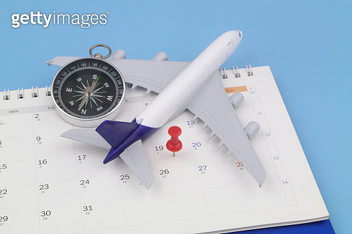 Airplane model with black compass and push pin on calendar page ...