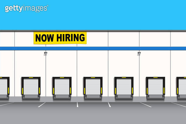 A logistics warehouse building with a Now Hiring banner sign ...