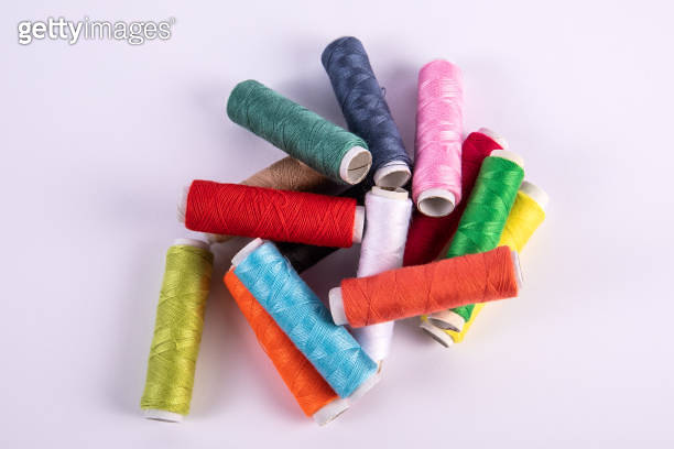 Stacked spools of thread for sewing in different colors on white ...
