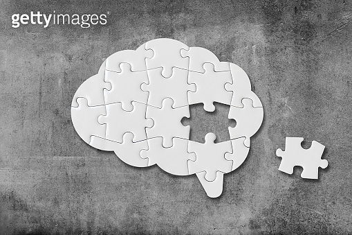 Brain shaped white jigsaw puzzle on concrete wall background, a missing ...
