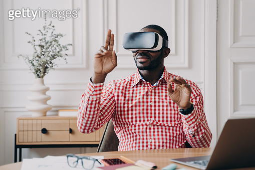 Focused Aframerican man in VR glasses enjoying augmented reality while ...