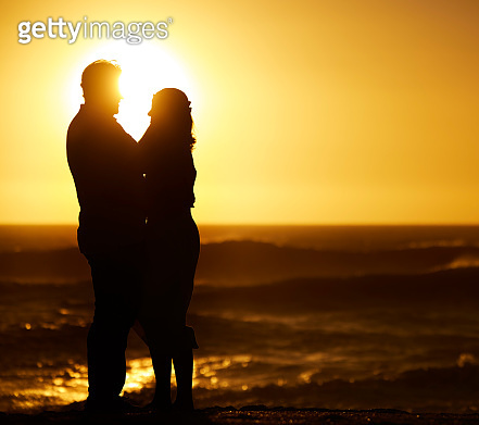 Silhouette of mature couple hugging at sunset. Senior couple being