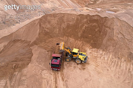 Wheel loader load sand in dump truck in open pit. Front end loader on ...