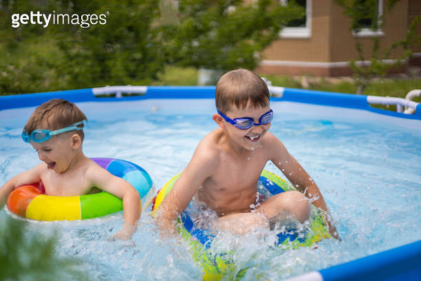 Two boys brothers in the outdoor outdoor pool near the house swim and ...
