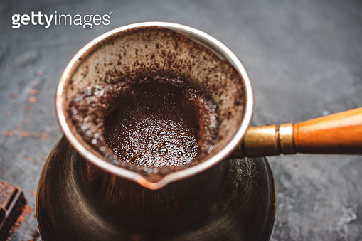 Fresh brewed coffee in the turkish jezva coffee pot on dark background ...