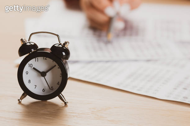 alarm clock with time running out. Students hands to take exams, write ...