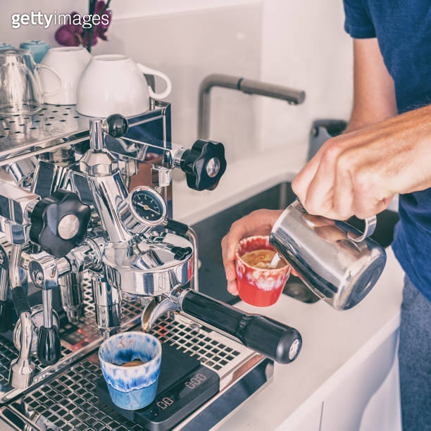 Making making coffee at home with espresso machine pouring steamed milk