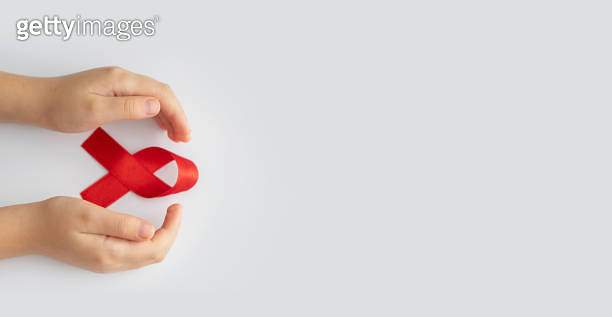 AIDs red ribbon in child hands on white background, symbol of struggle ...