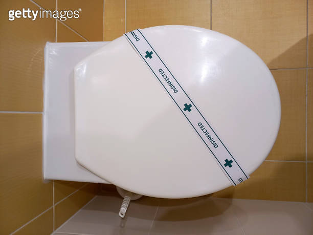 Top view of white toilet seat in toilet. There is a DISINFECTED strip ...
