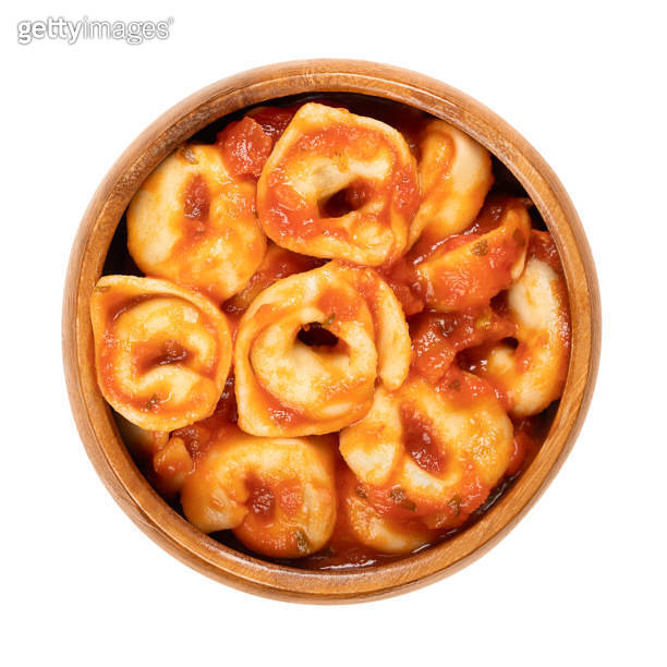 Boiled tortellini, dumplings dressed in tomato sauce, in a wooden bowl