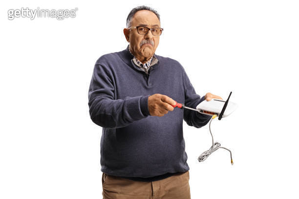 Confused mature man fixing router with a screwdriver (1691804574) - 게티이미지뱅크