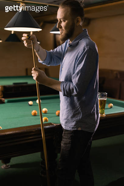Attractive man snooker, billiard player, chalking the cue in motion ...