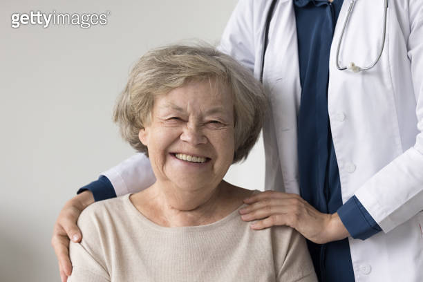 Happy positive elderly patient woman posing near geriatrician doctor ...