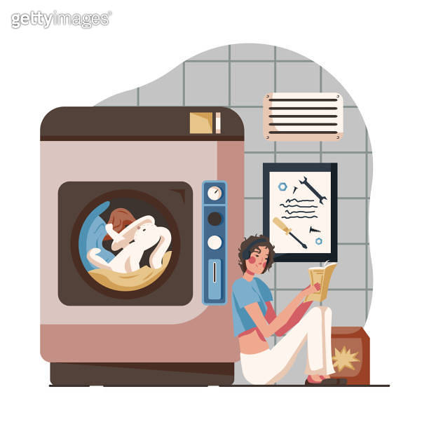 Smiling lady sitting near big washing machine, holding book and reading ...