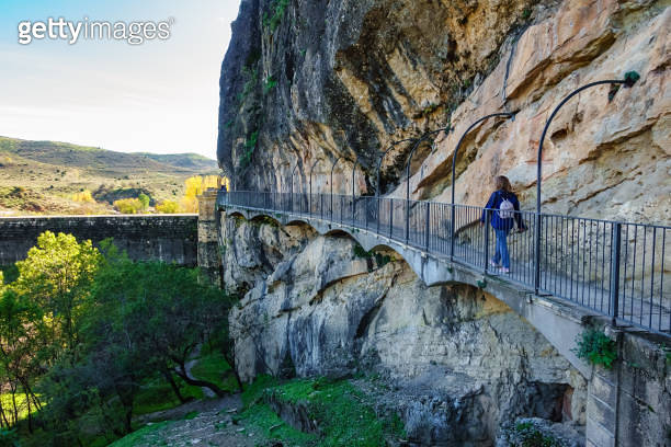 Woman hiker walking along the path hanging from the rock wall at the ...