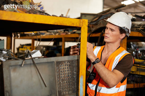 factory worker picking scrap metal on shelf in old warehouse ...
