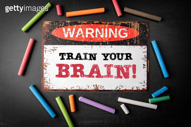 Train Your Brain. Metal warning sign and colored pieces of chalk on a ...