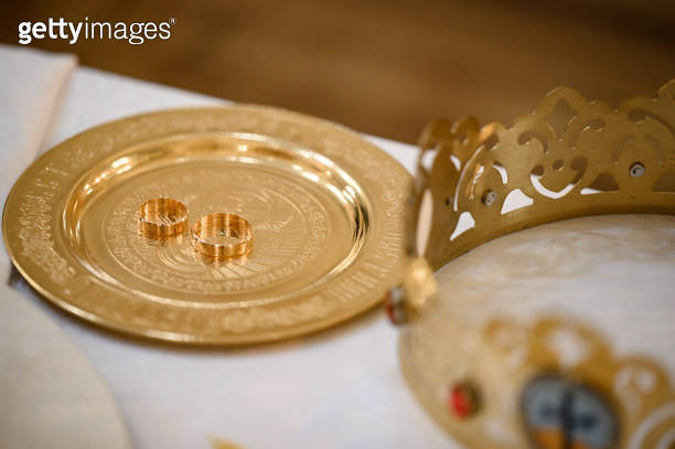 Wedding rings stand on a tray in the church for consecration with water ...