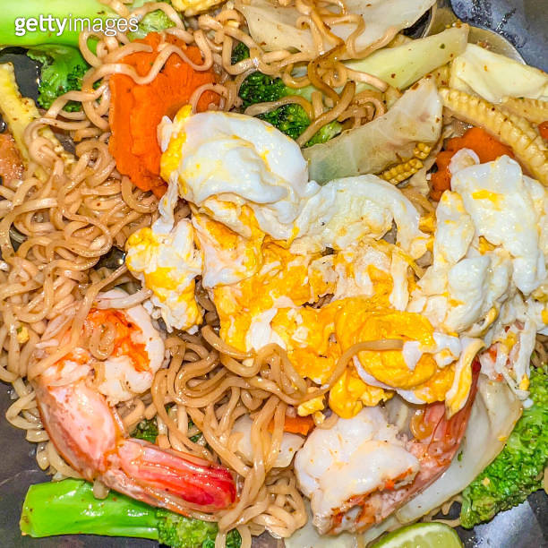 Delicious and tasty Yellow Thai egg noodles with shrimp prawns and mixed green vegetables and