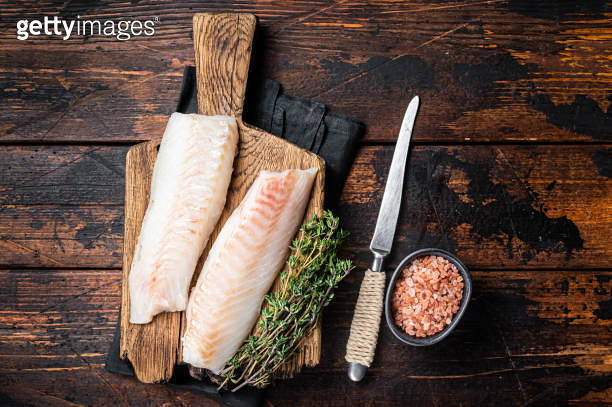 Cod fish fillets, raw codfish with thyme on wooden board. Wooden ...
