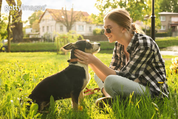 Teenage girl with her cute dog resting on green grass in park 이미지 ...