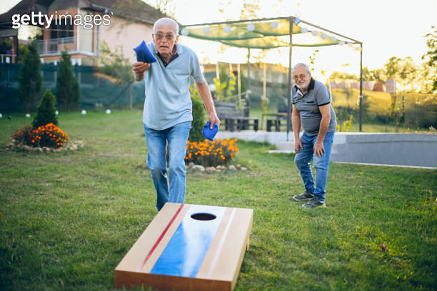 Two old friend play corn hole in backyard 이미지 (1742958170) - 게티이미지뱅크