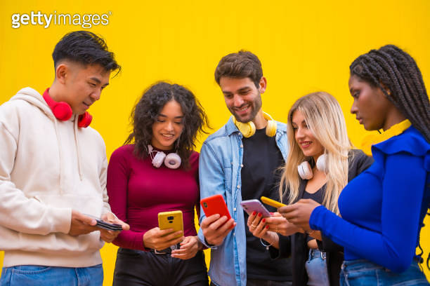 Low angle view of a group of young multi-ethnic teenage friends using ...
