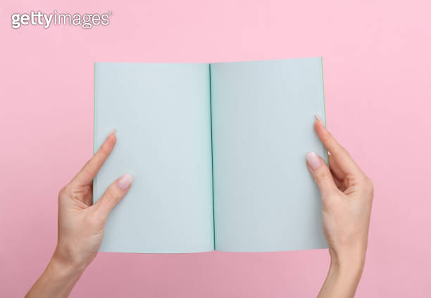 Female hands hold a notepad with blue sheets of paper on a pink pastel ...