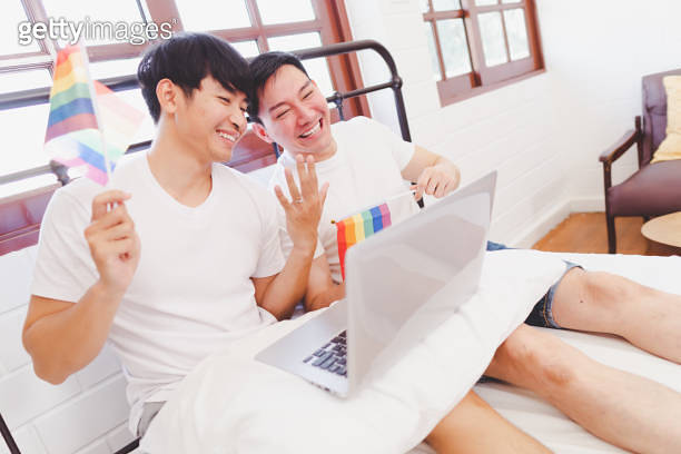 Happy engaged asian gay couple waving lgbt rainbow flag and VDO call to ...