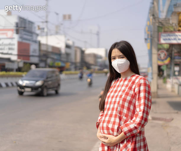 Asian pregnant woman she is in the middle of the road wear a PM2.5 dust