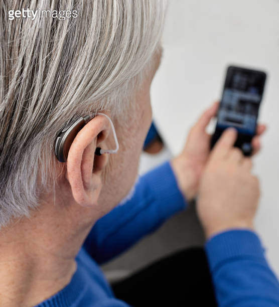 Hearing impaired senior man adjusting settings for his BTE hearing aid
