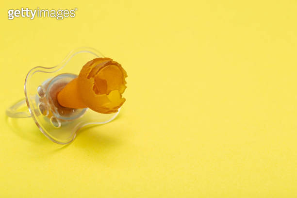 A chewed baby pacifier on a yellow background. Concept of teething in ...
