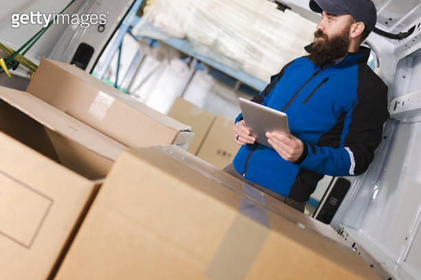 Deliverer prepares packages for delivery and uses a digital tablet 이미지 ...