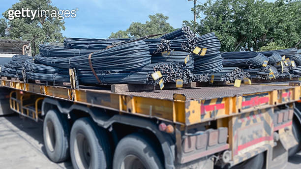 A truck with a long trailer carries rebar for building construction ...