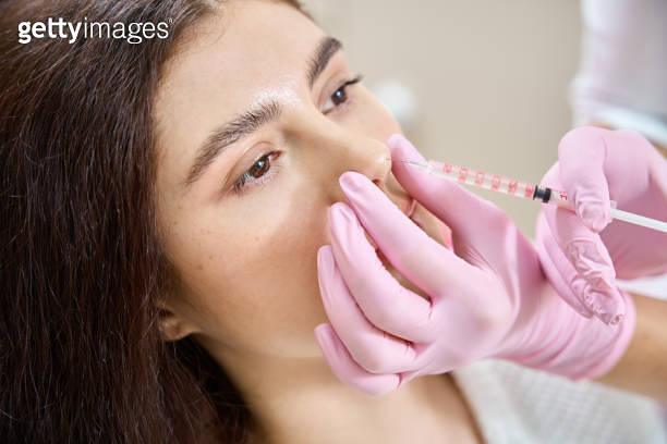 Beauty therapist performing injection rhinoplasty on young woman 이미지 ...