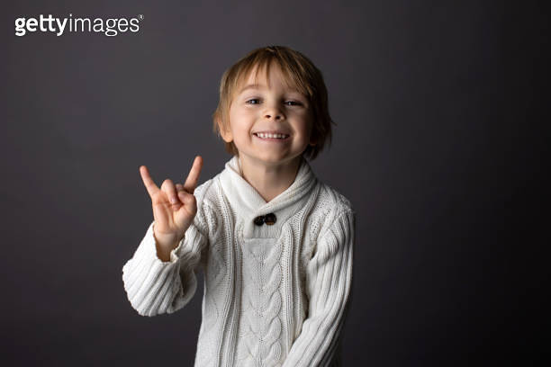 Cute little toddler boy, showing gesture in sign language on gray ...