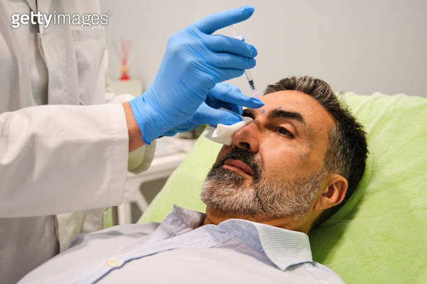 A man is getting Botox for forehead wrinkles by a aesthetic doctor in a ...