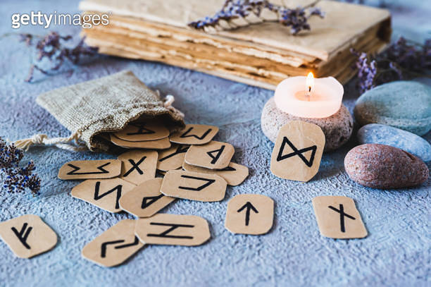 Fortune telling cardboard runes scattered from a bag, a candle, an old ...