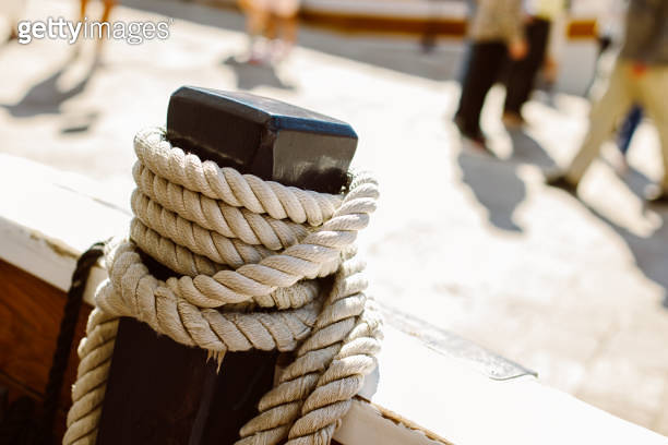 Close-up of old rope on a sailboat deck. Blurred marina on a background ...