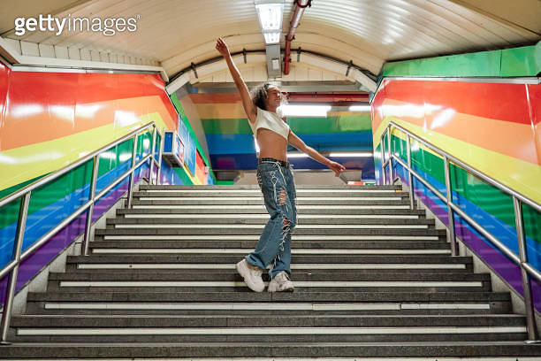 full view of a gay man dancing in the middle of the stairs of a subway ...