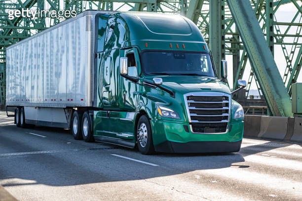 Green powerful big rig semi truck transporting cargo in dry van semi ...