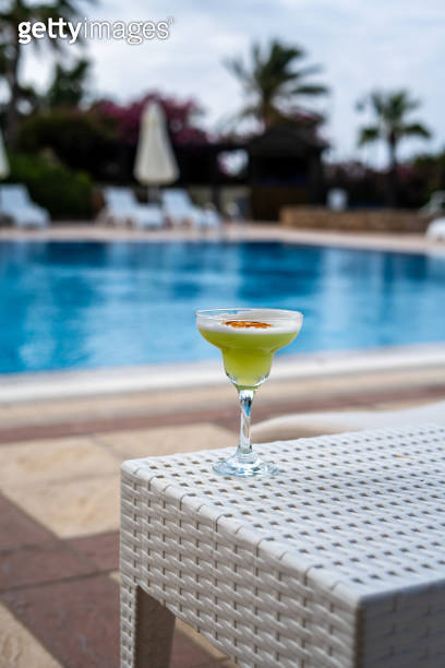 cocktail is on table at swimming pool focus on foreground swimming pool ...